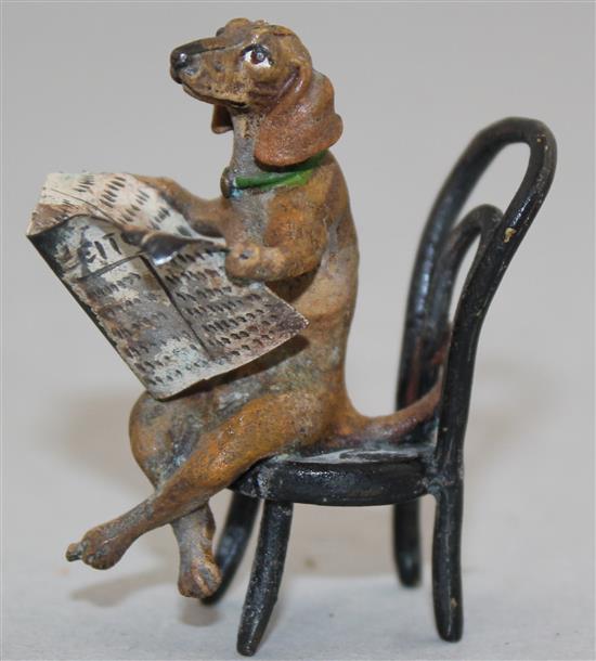 A miniature cold painted bronze model of a seated Dachshund reading a newspaper, in the manner of Franz Bergman, 2in.